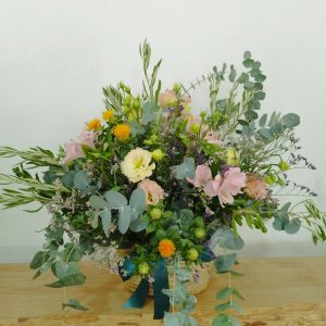 Composición floral de aspecto campestre sobre una cesta tipo Capazo. Utilizamos Eucalipto flores de fácil secado para que duren, siempre bonitas, durante meses.